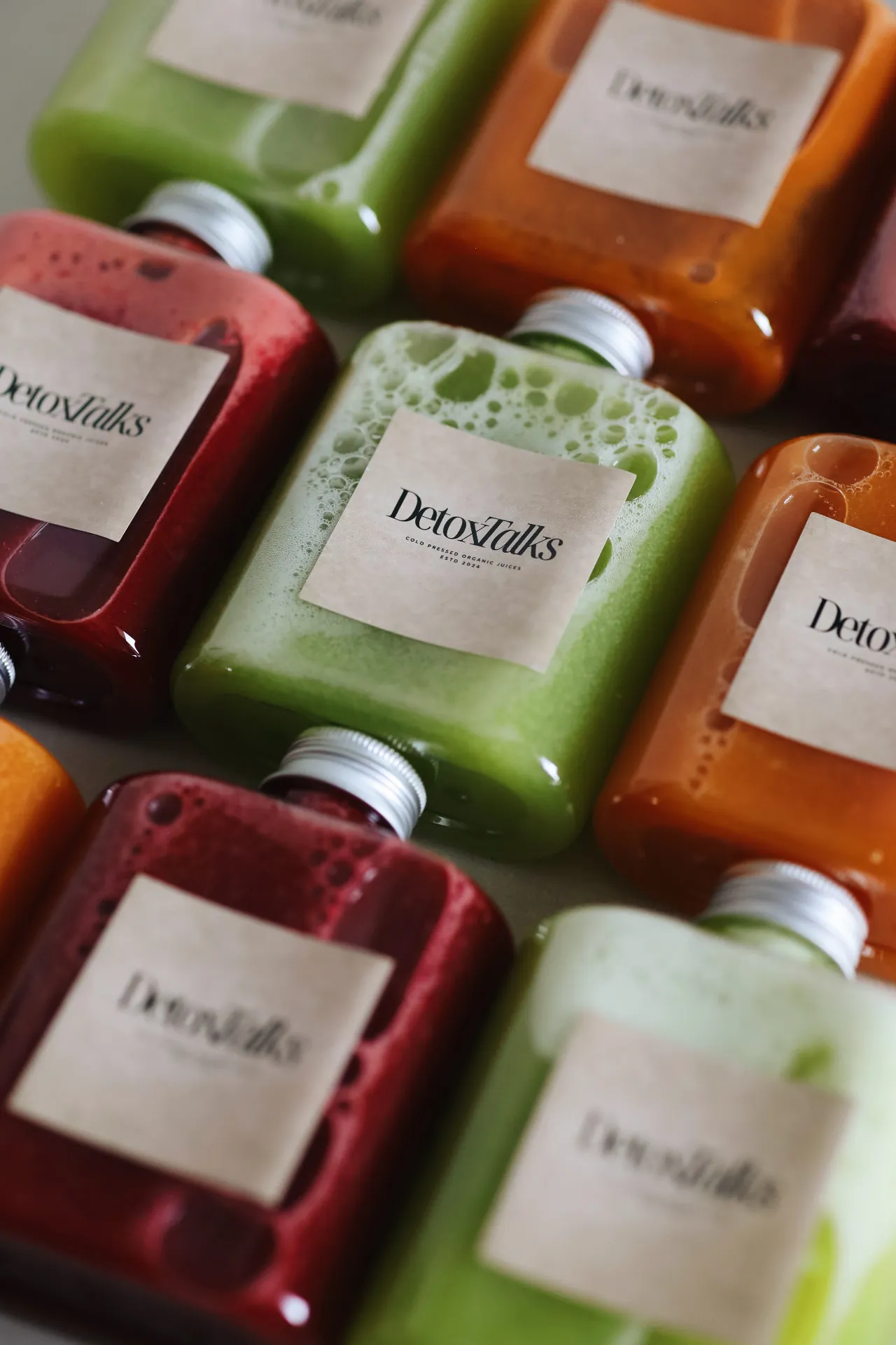 Rows of Detox Talks Club cold-pressed juice bottles in green, red, and orange